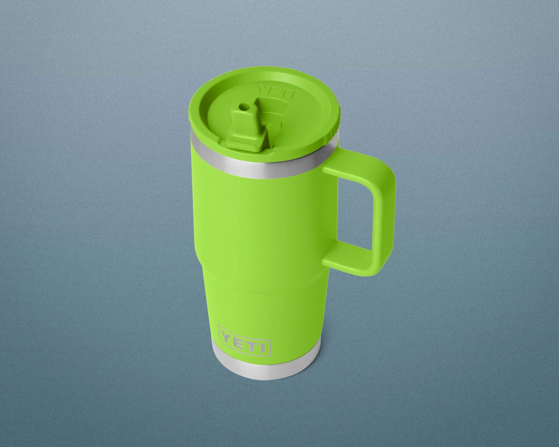 Bright green YETI insulated travel mug with handle and spill-resistant lid on a blue-gray background.