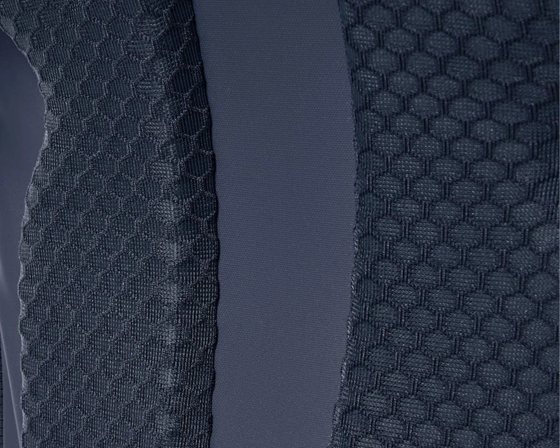 Close-up of dark blue fabric with honeycomb textured knit panels on either side of a smooth central strip.