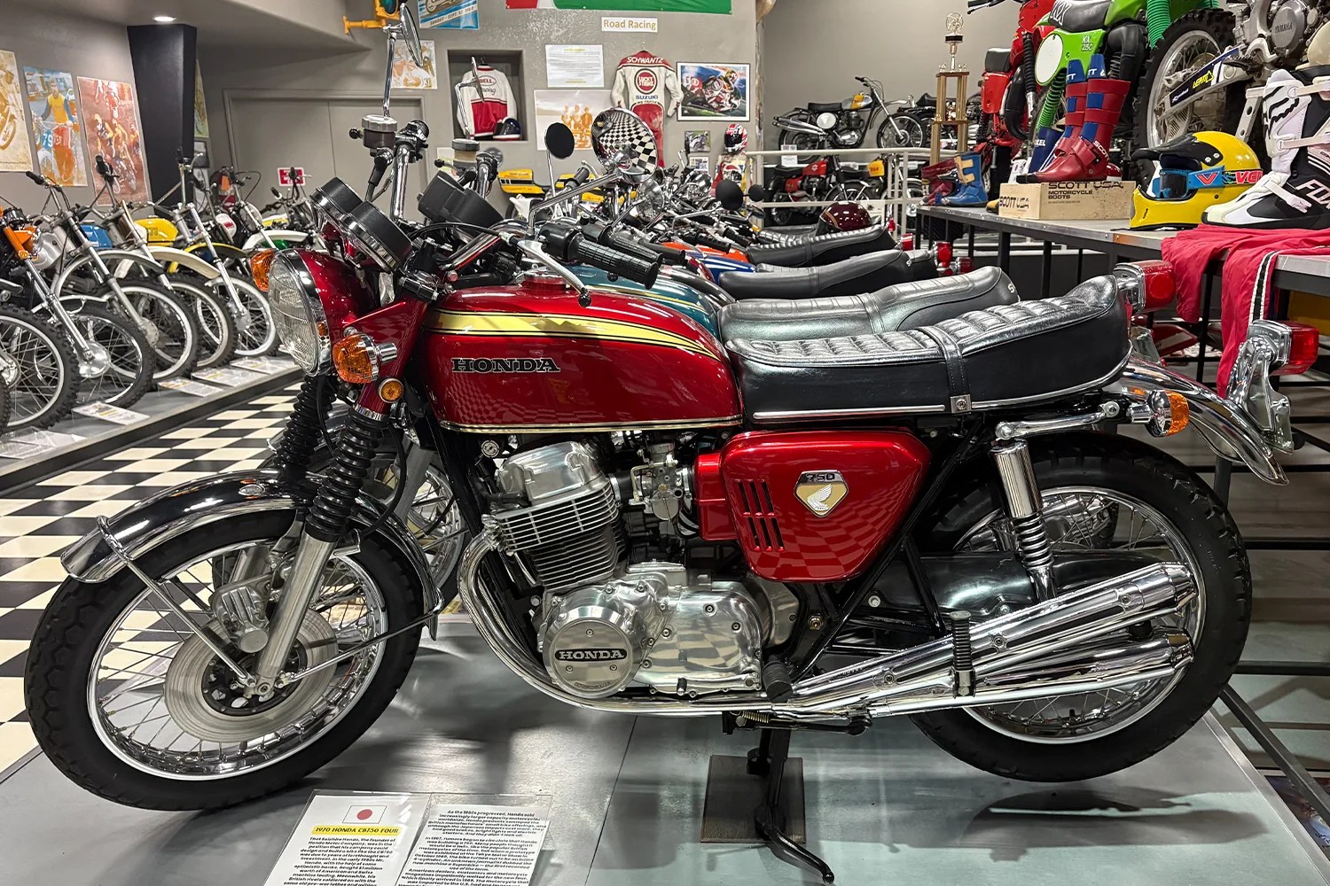 Red 1970 Honda CB750 Four motorcycle with chrome details on display in a museum.