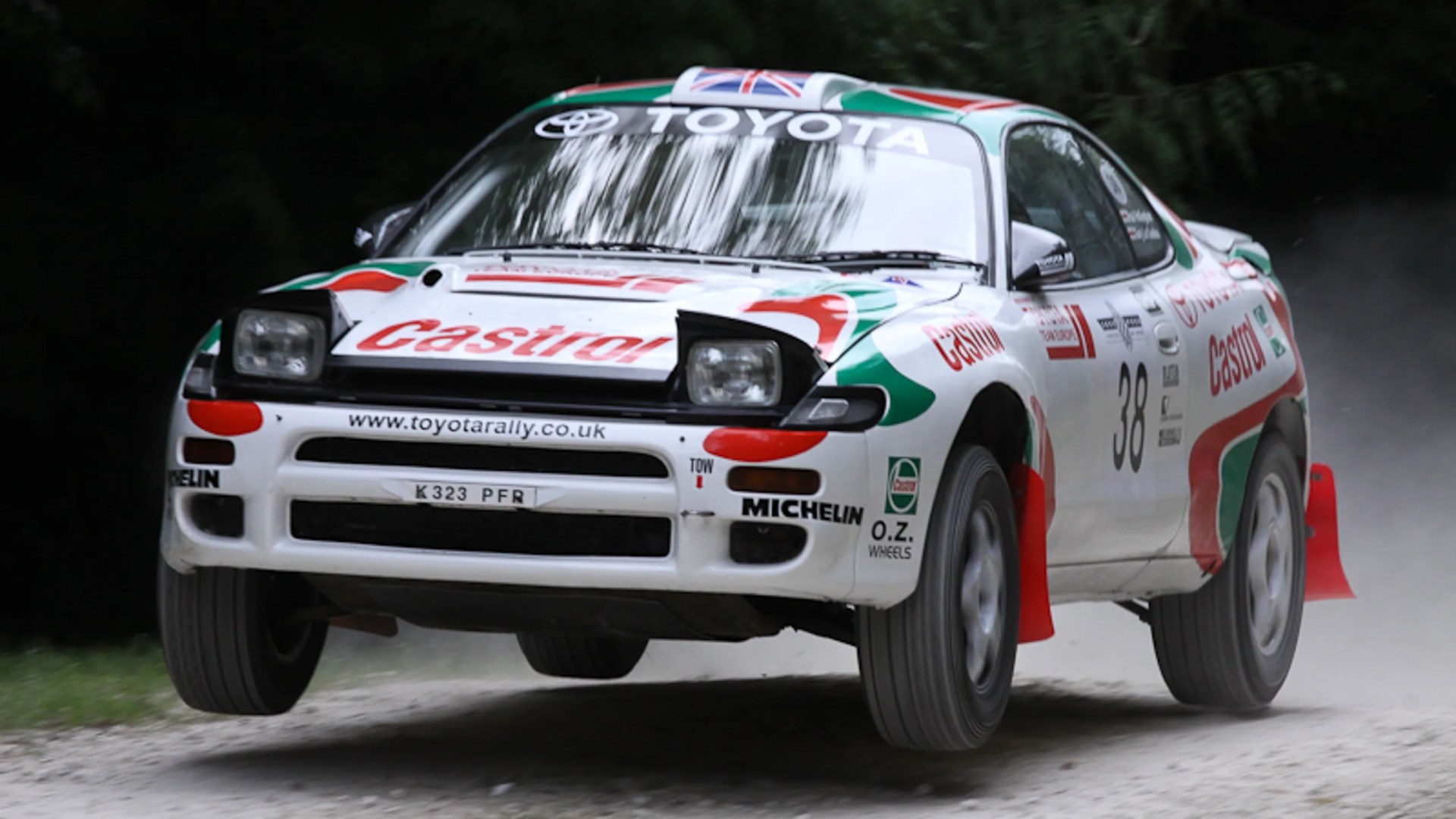 White Toyota rally car with Castrol and Michelin logos airborne on a dirt road.