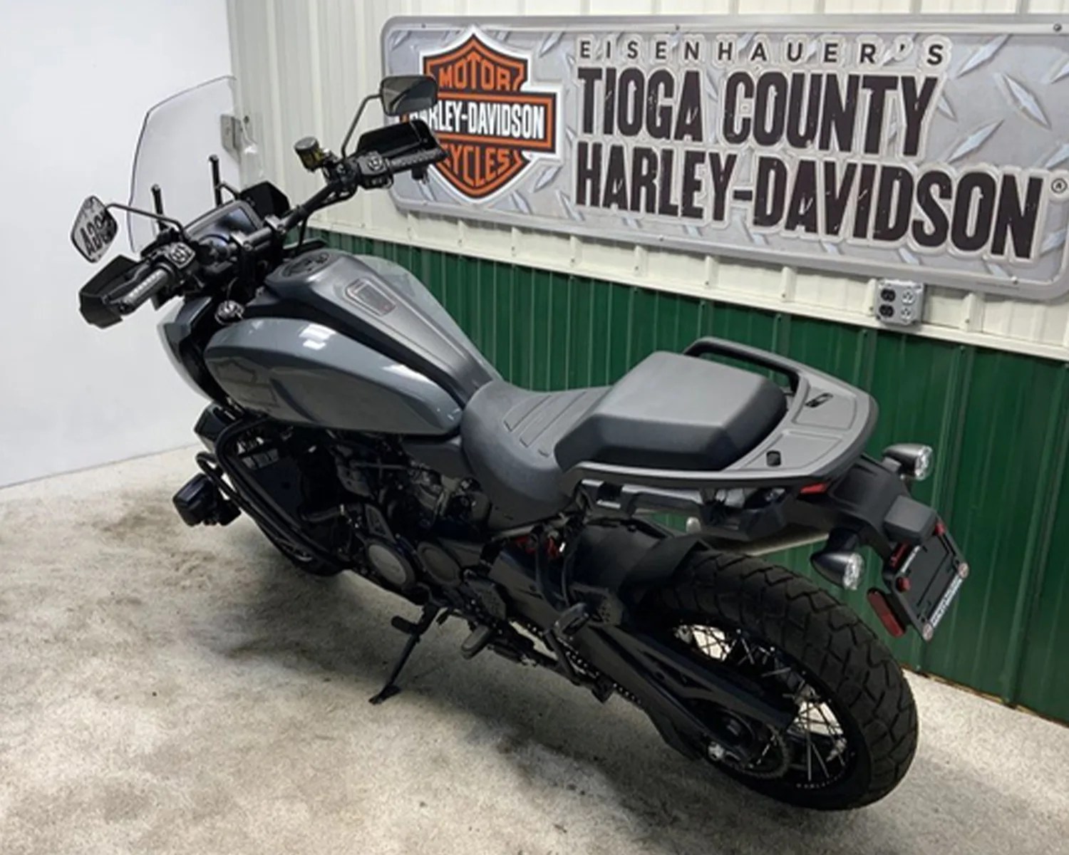 Gray and black Harley-Davidson motorcycle parked indoors near a Tioga County Harley-Davidson sign.