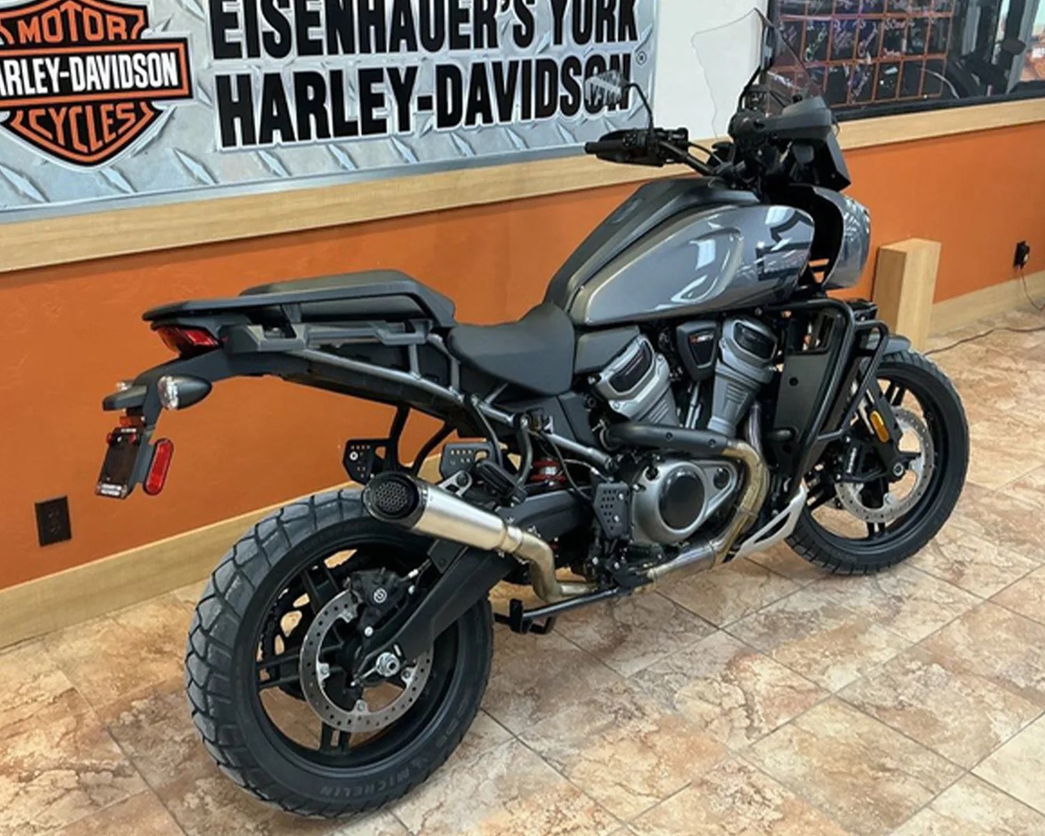 Gray and black Harley-Davidson adventure motorcycle with knobby tires parked indoors on tiled floor.