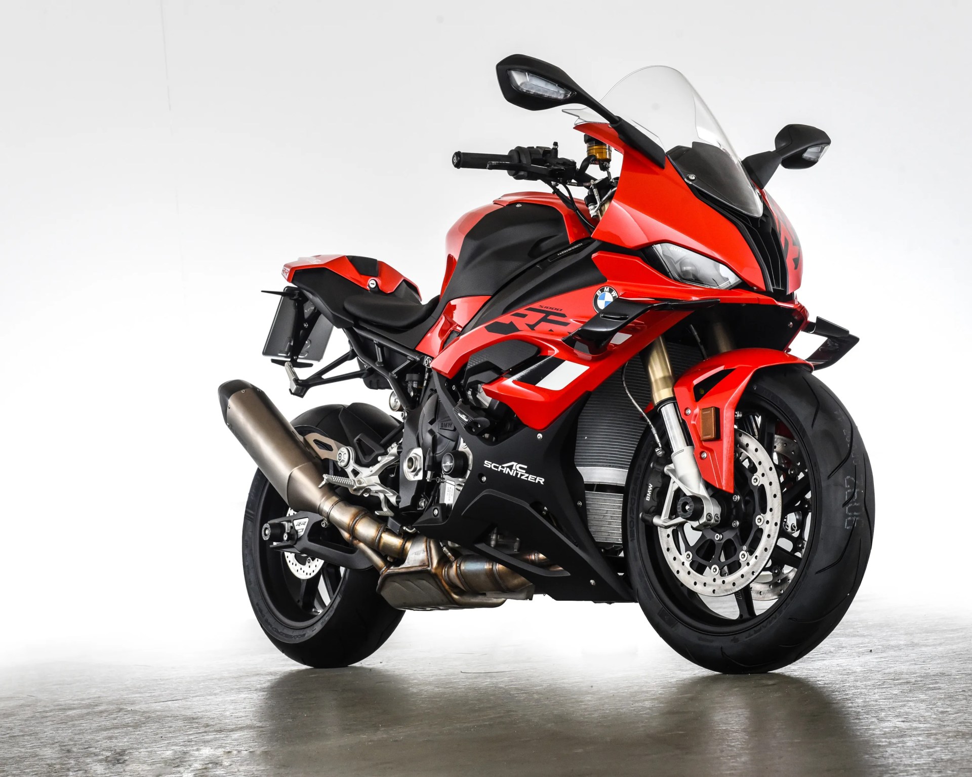Red and black BMW sport motorcycle with AC Schnitzer branding on a gray floor.