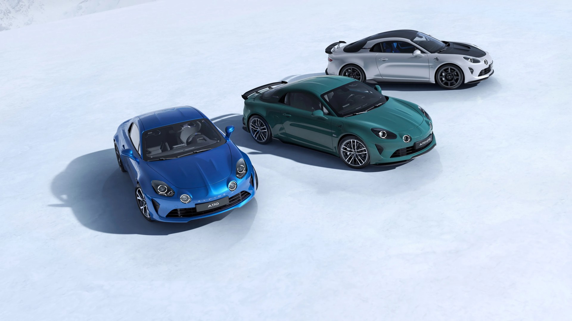 Three Alpine A110 sports cars in blue, green, and white with black roofs parked on a light gray surface.