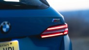 Rear view of a blue BMW M5 with illuminated taillights and a partially visible license plate.