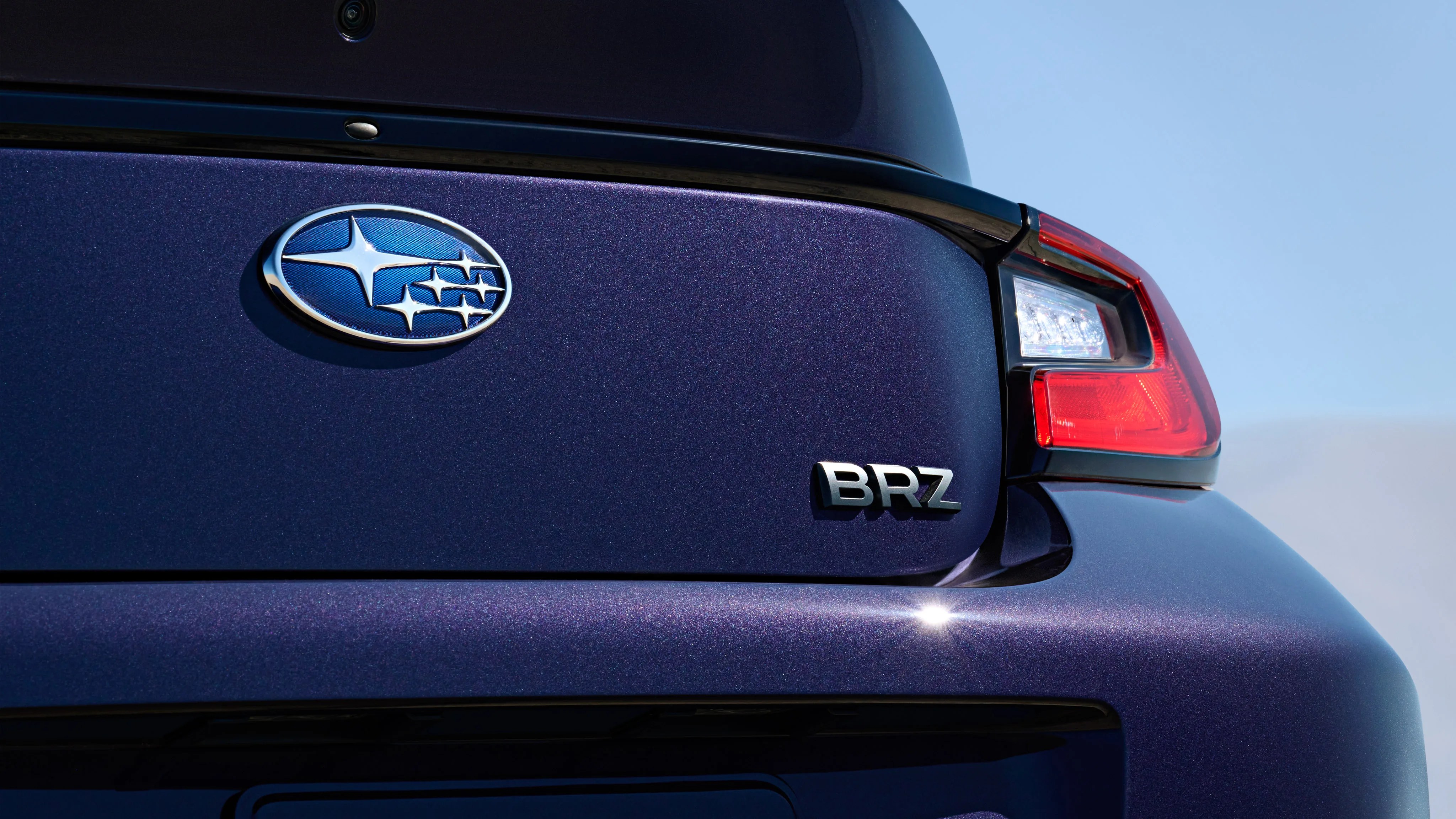 Close-up of the rear of a dark blue Subaru BRZ showing the Subaru logo, BRZ badge, and right taillight.