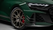 Close-up of a green Audi car's front wheel with bronze multi-spoke rim, red brake caliper, and LED headlight.