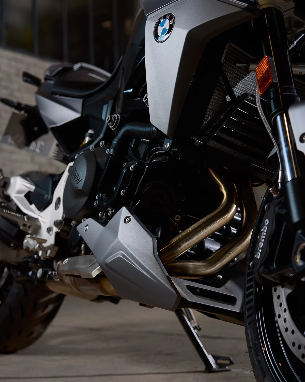 Close-up of a silver and black BMW motorcycle engine and exhaust pipes with Brembo brake caliper.