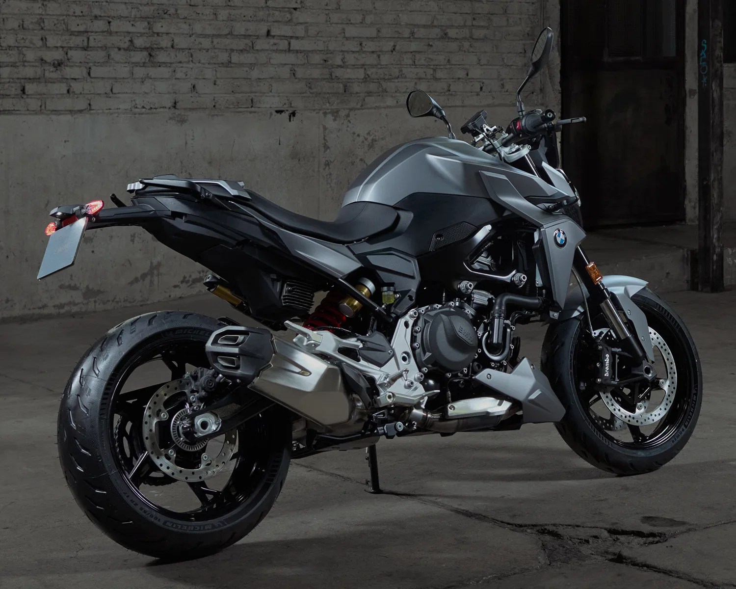 Matte gray and black BMW motorcycle with dual disc brakes and Michelin tires parked indoors on a concrete floor.