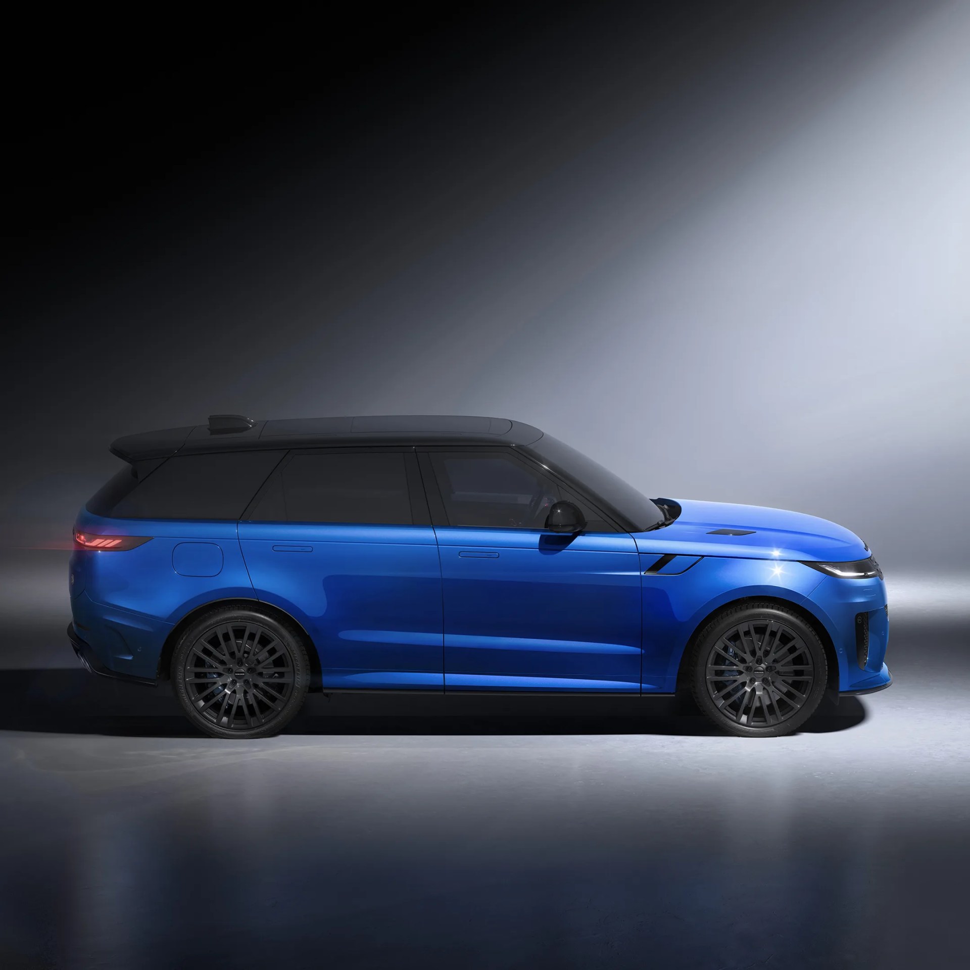 Blue luxury SUV with black roof and dark alloy wheels in a studio setting.