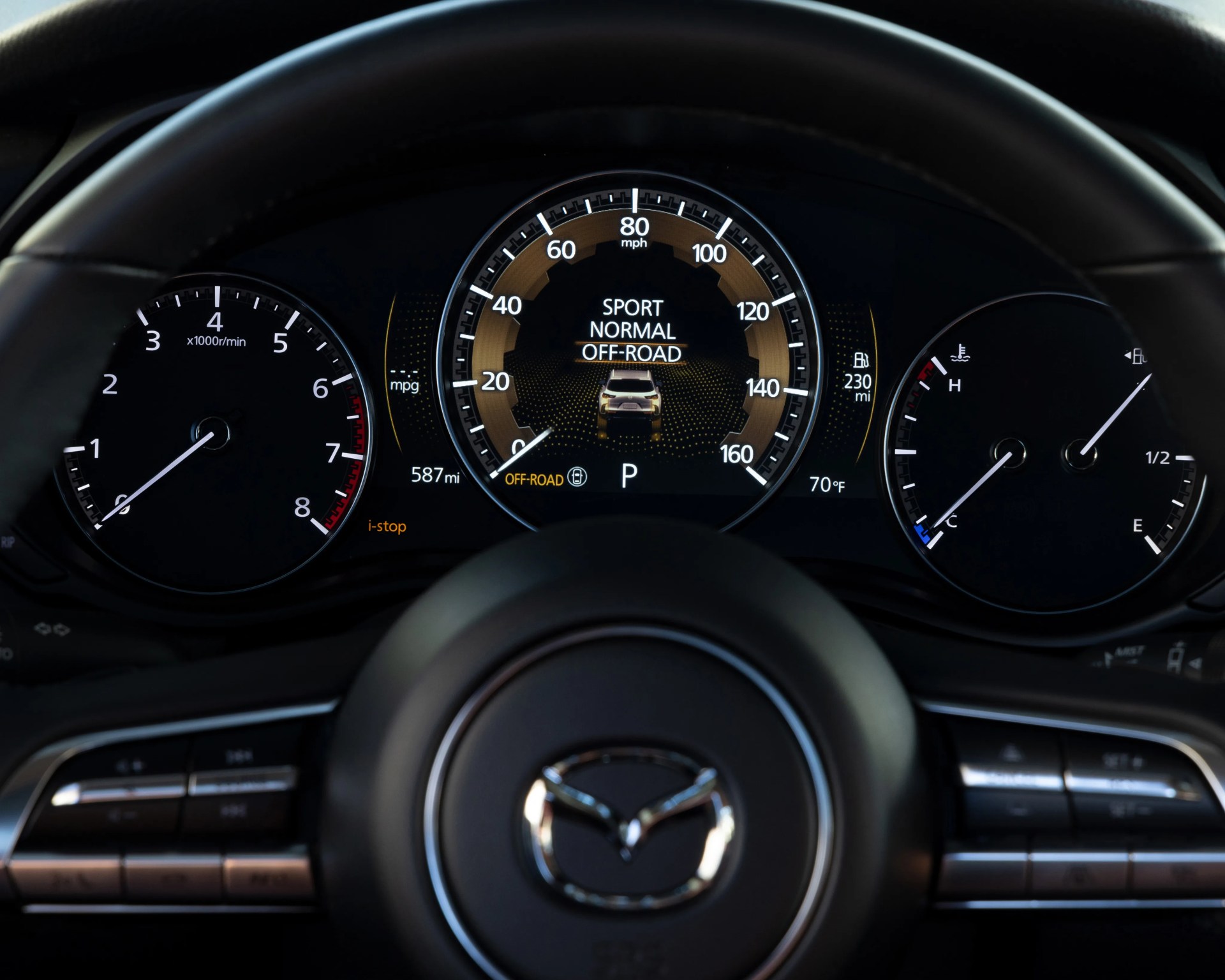 Mazda car dashboard with digital speedometer showing 80 mph, tachometer, fuel gauge, temperature gauge, and driving mode options.