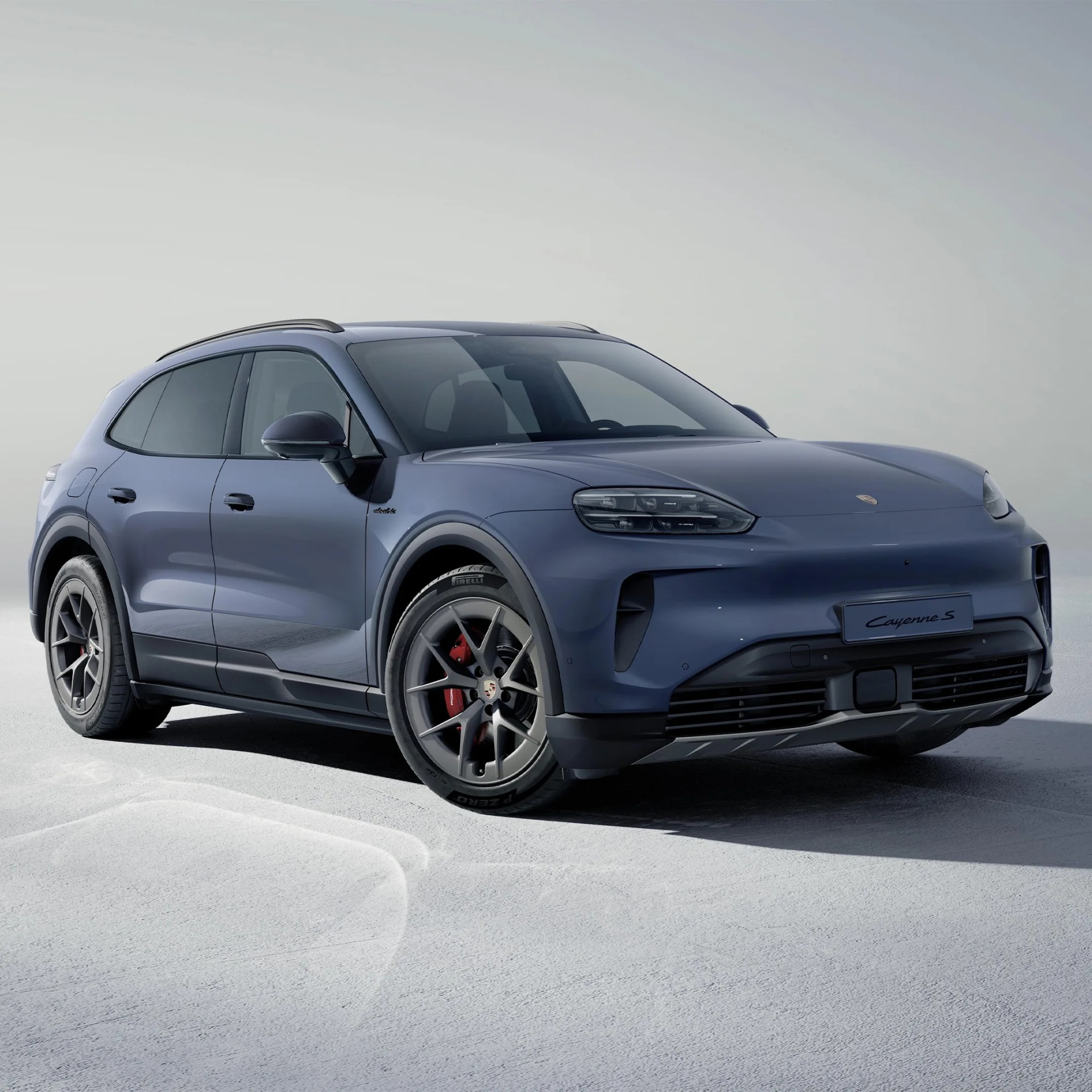 Blue Porsche Cayenne S SUV with black trim and red brake calipers on a light gray surface.