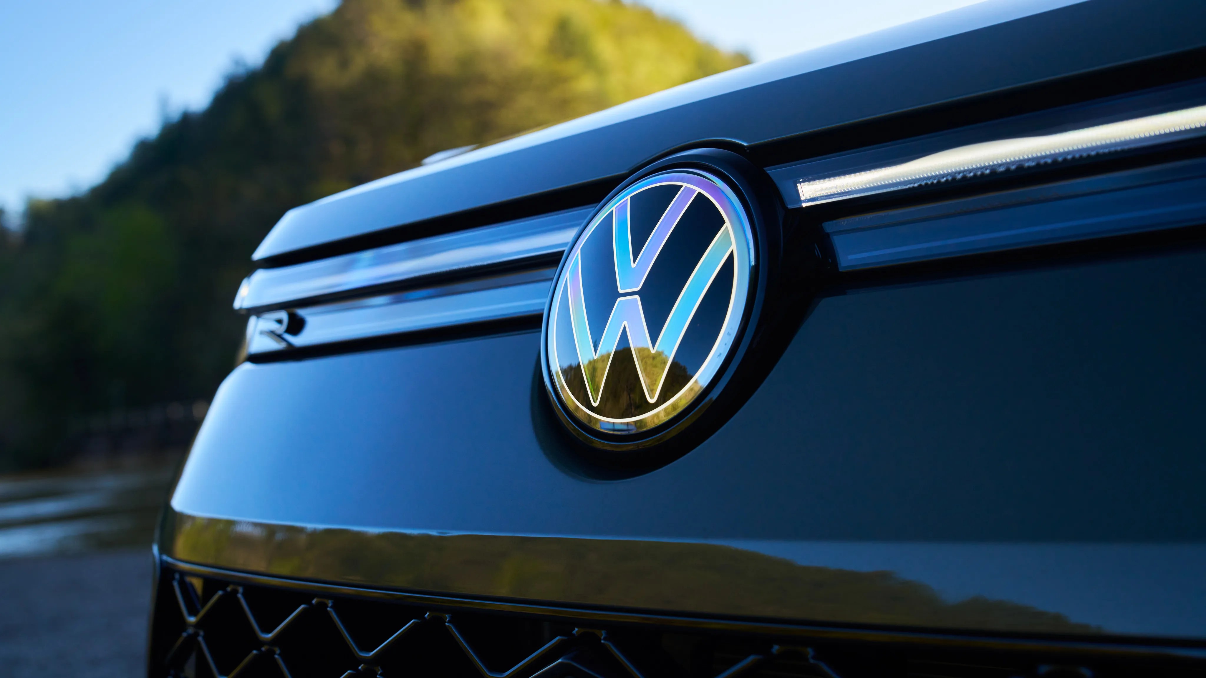 Close-up of a black Volkswagen car front grille with illuminated VW logo and LED light strip.