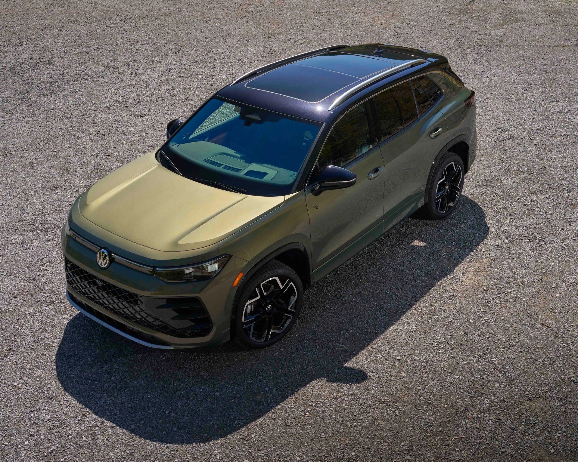 Green Volkswagen SUV with black roof and alloy wheels parked on gravel.