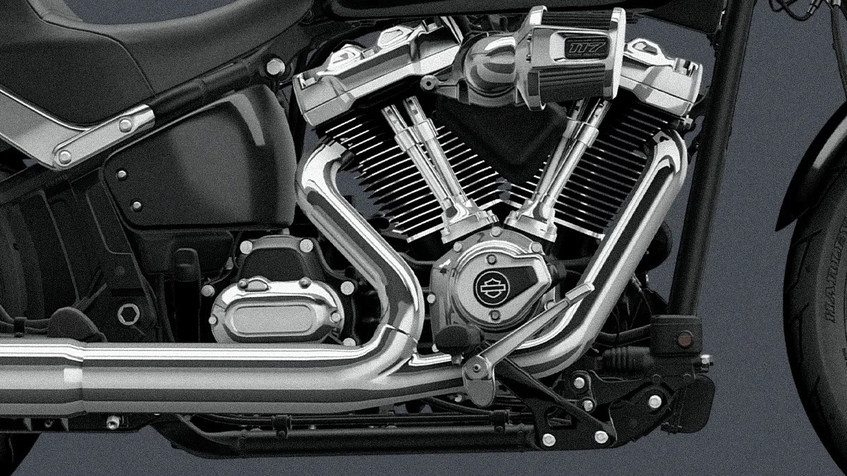 Close-up of a chrome V-twin motorcycle engine with visible exhaust pipes and part of the black frame.