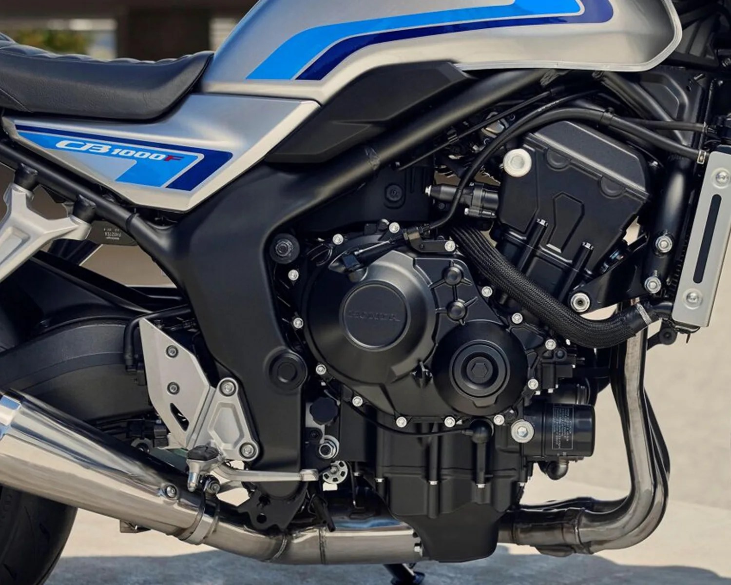Close-up of a black and silver Honda CB1000F motorcycle engine with blue accents on the fuel tank.