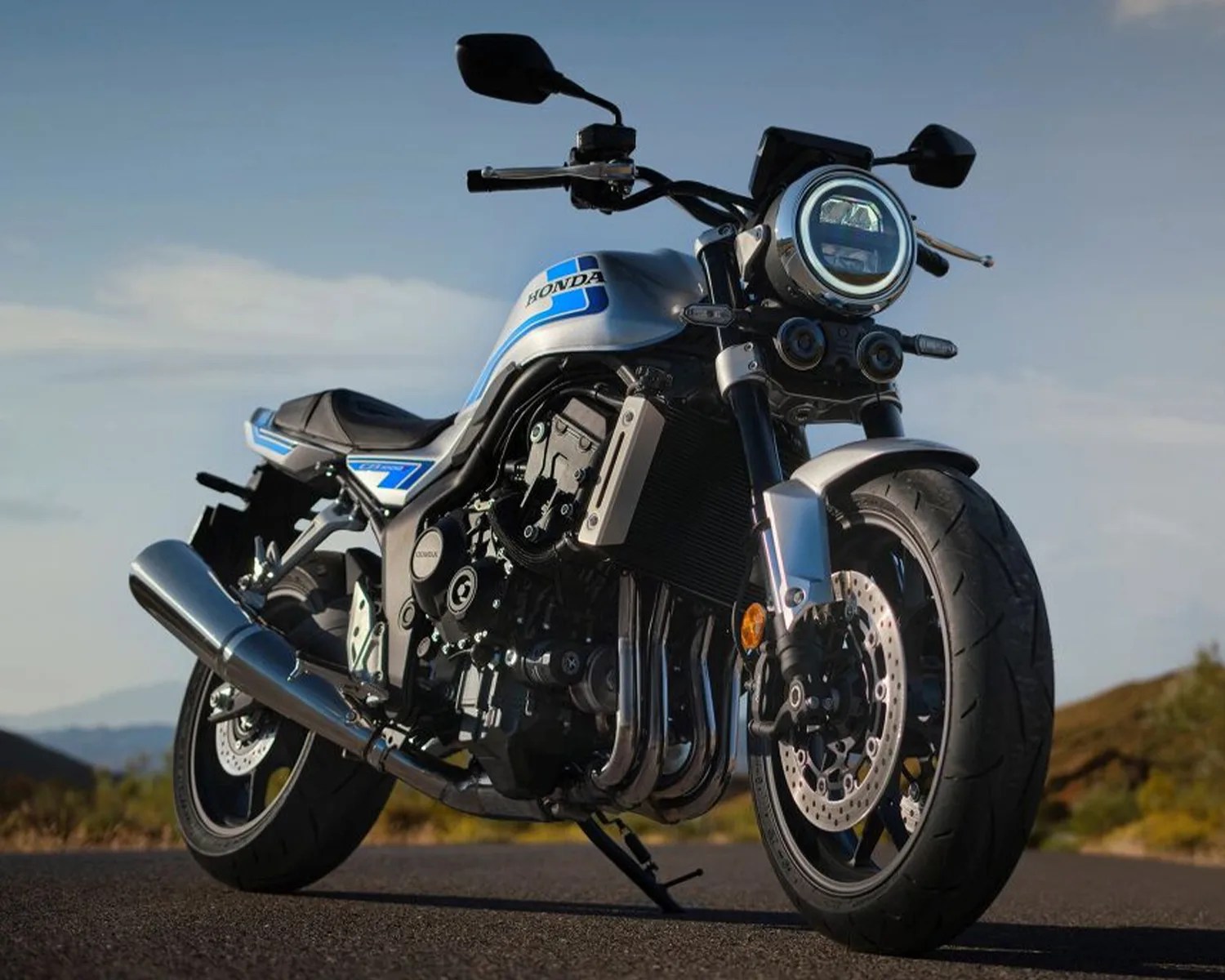 Silver and blue Honda motorcycle with round headlight and black tires parked on a road.