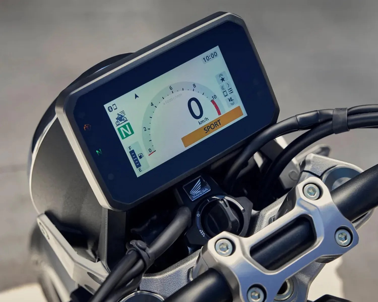 Close-up of a motorcycle digital dashboard showing 0 km/h speed, SPORT mode, and Honda logo below the display.
