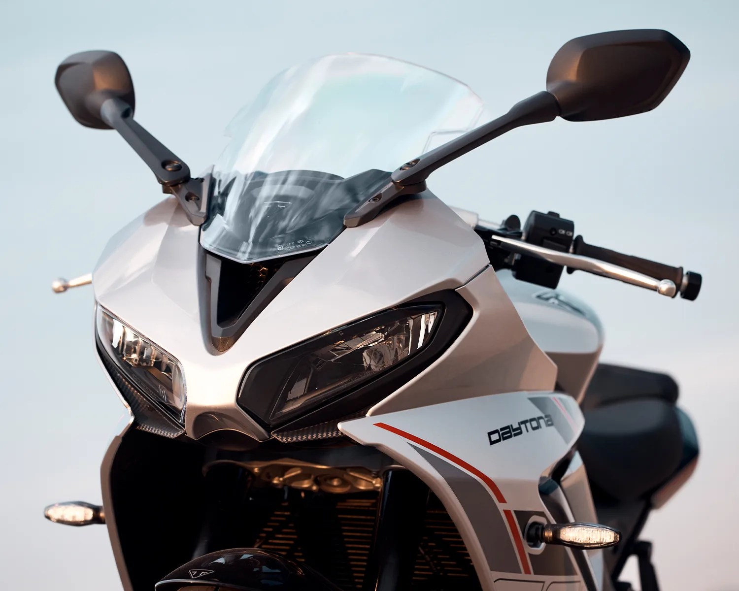 Front view of a white Triumph Daytona motorcycle with clear windshield and black side mirrors.