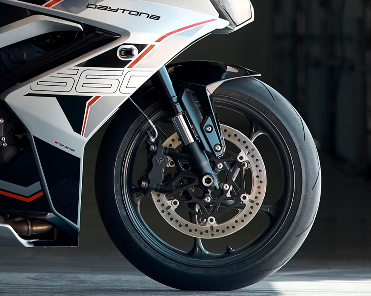 Front wheel of a white and black Daytona 560 motorcycle with disc brake and slick tire.