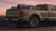Olive green Ford Tremor Super Duty pickup truck loaded with camping gear in the bed at sunset.