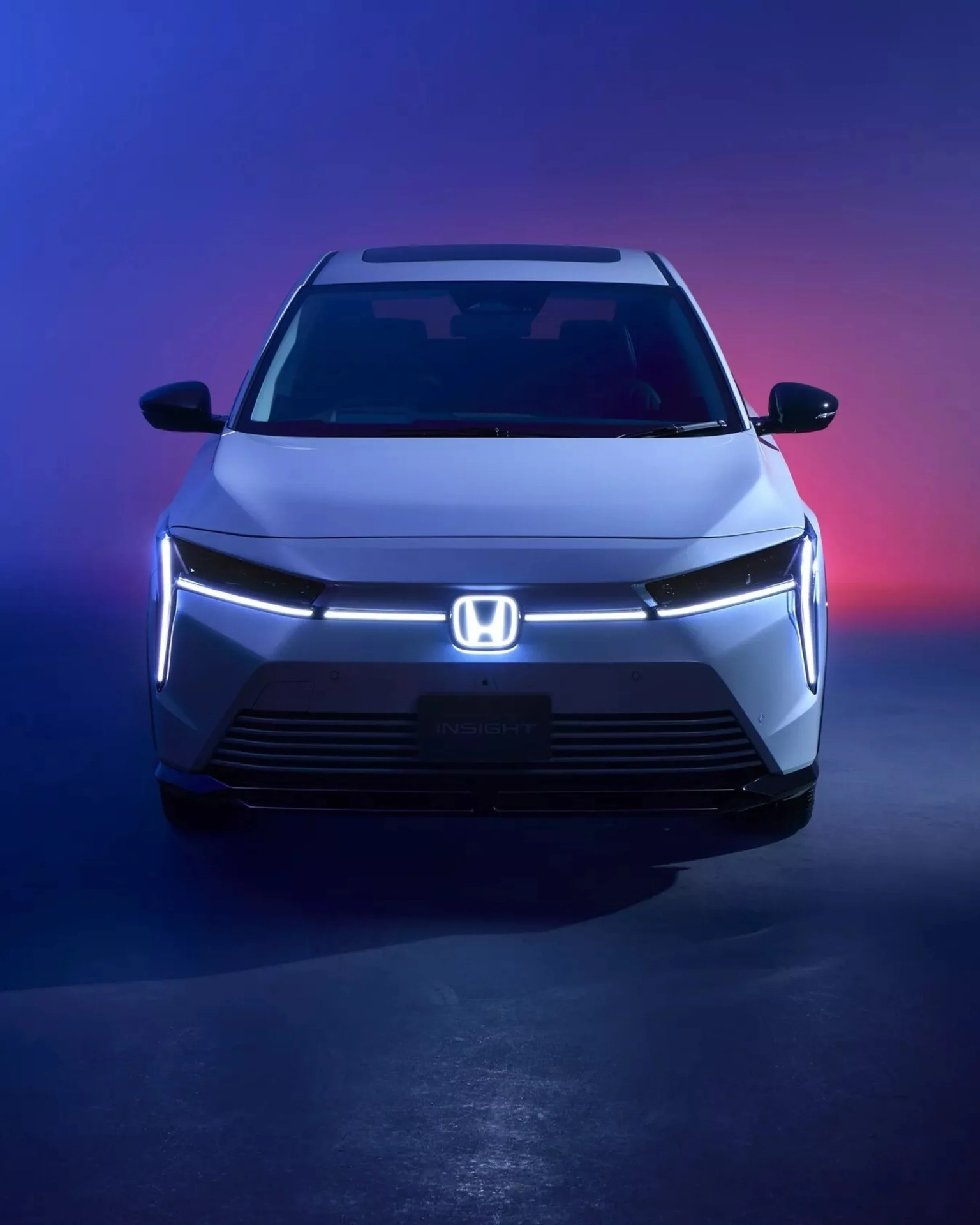 Front view of a white Honda Insight with illuminated LED headlights and logo against a blue and purple gradient background.