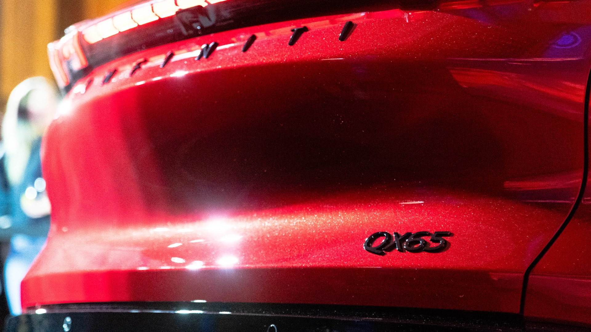 Rear side of a red Infiniti QX65 vehicle with black model lettering.