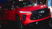 Red Infiniti SUV with black grille and LED headlights, front passenger door open, shown indoors.