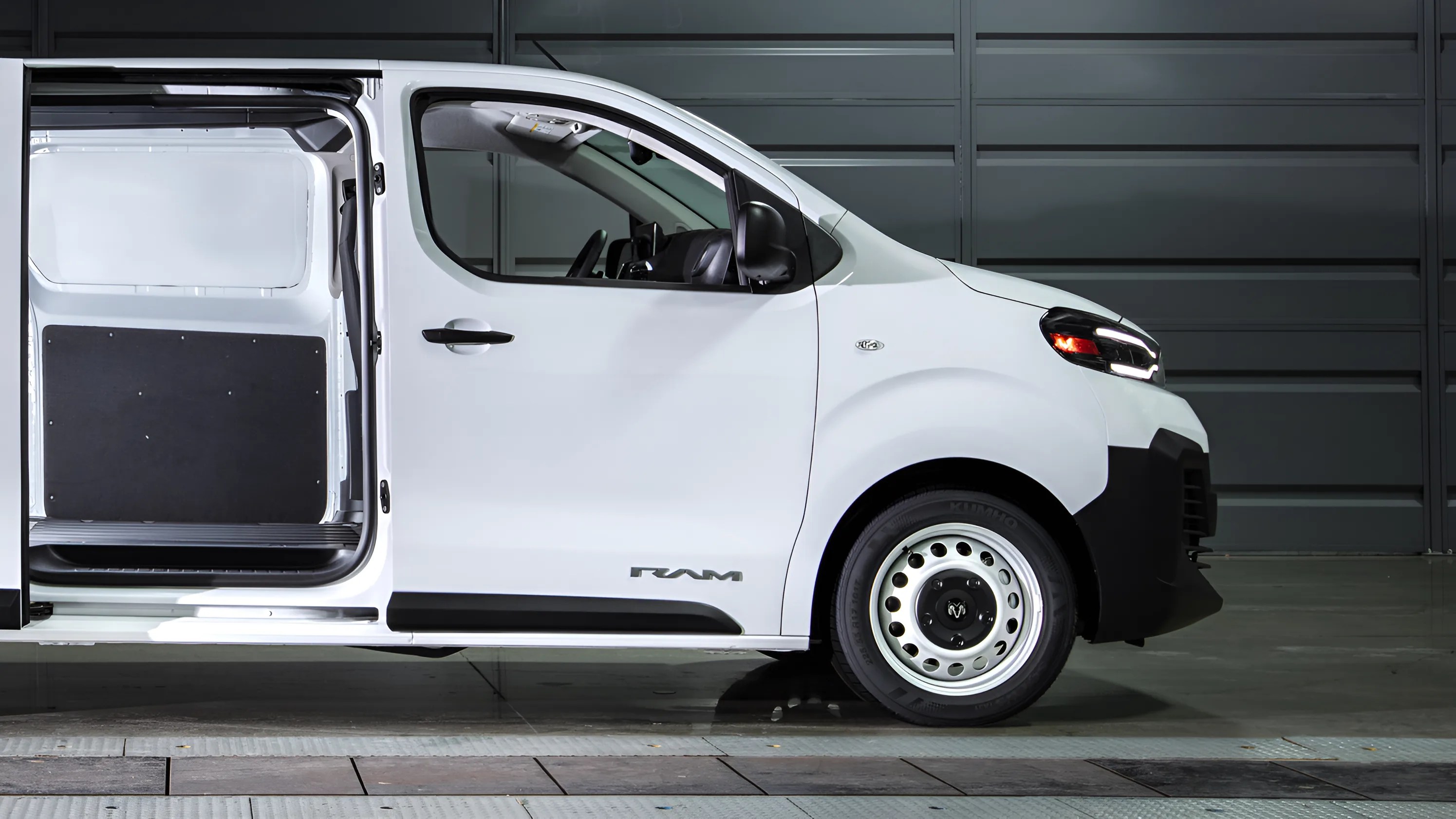 White RAM cargo van with sliding side door open, showing empty interior and steel wheels.