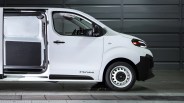 White RAM cargo van with sliding side door open, showing empty interior and steel wheels.