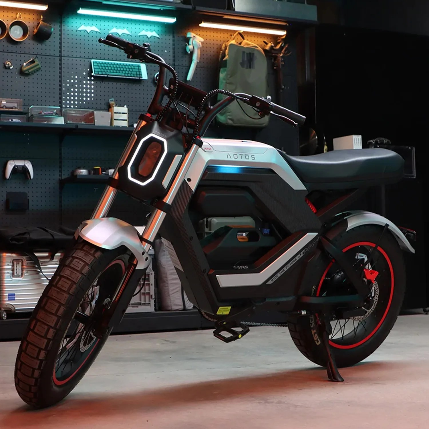 Electric bike with a black and silver frame, red-rimmed tires, and a hexagonal front light in a garage setting.