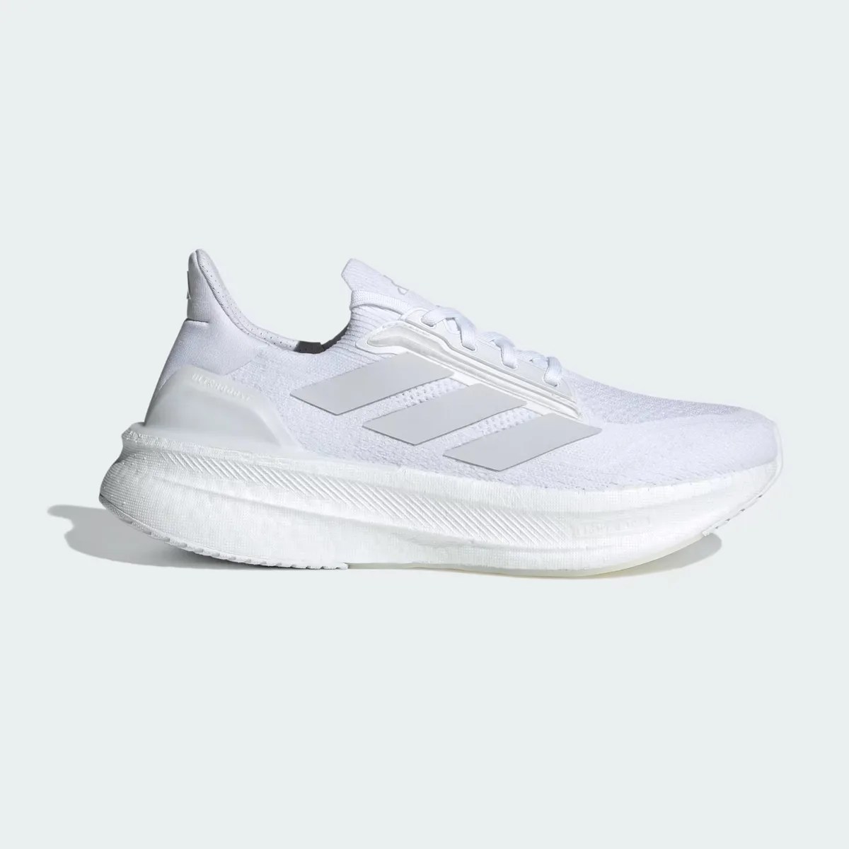 All-white Adidas running shoe with knit upper, three side stripes, and thick cushioned sole.