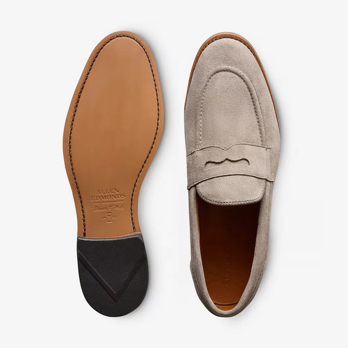 Pair of light gray suede penny loafers with leather sole and black rubber heel patch, one shoe showing top and the other sole.