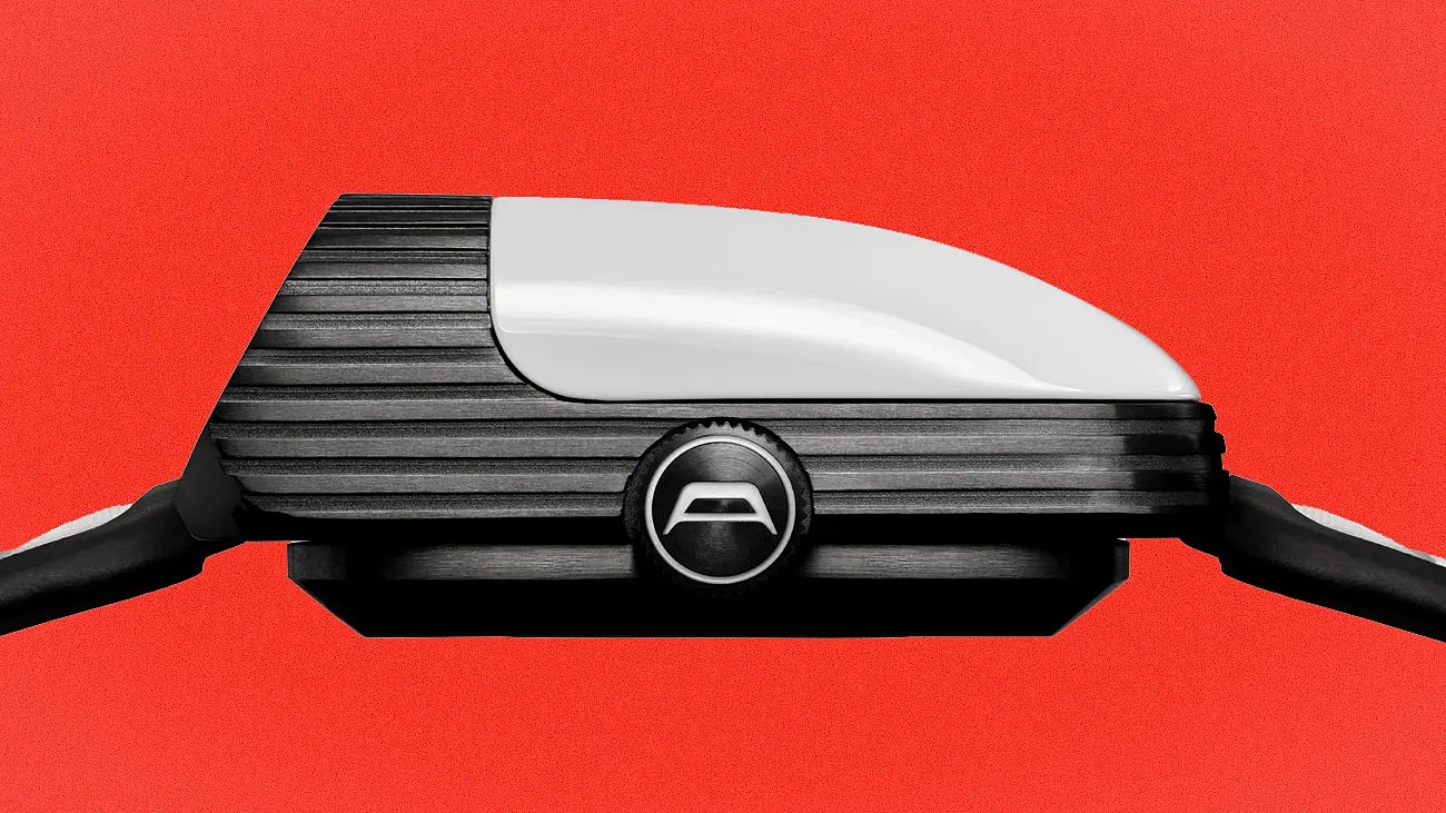 Side profile of a black and white wristwatch with a ridged texture and a round crown featuring a stylized "A" logo on a red background.