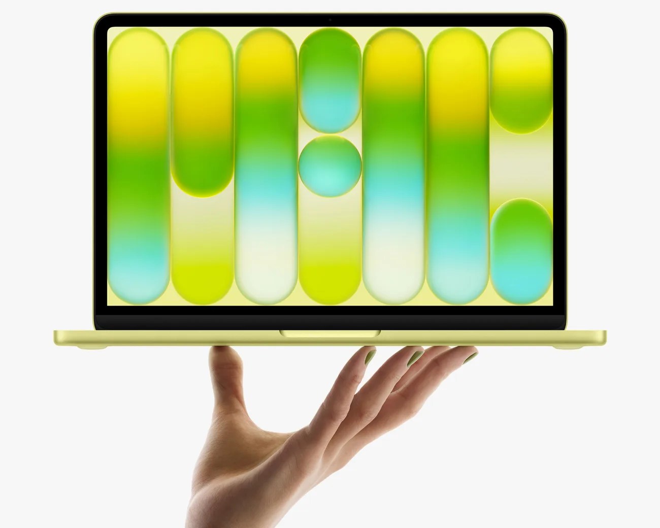 Yellow laptop with a colorful abstract wallpaper held on a hand with matching yellow-green nail polish.