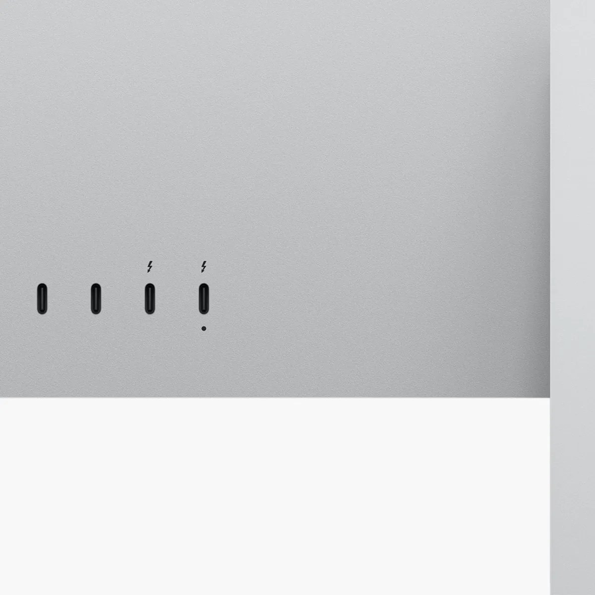 Close-up of four black USB-C ports on a silver-gray device surface, two marked with lightning bolt symbols.