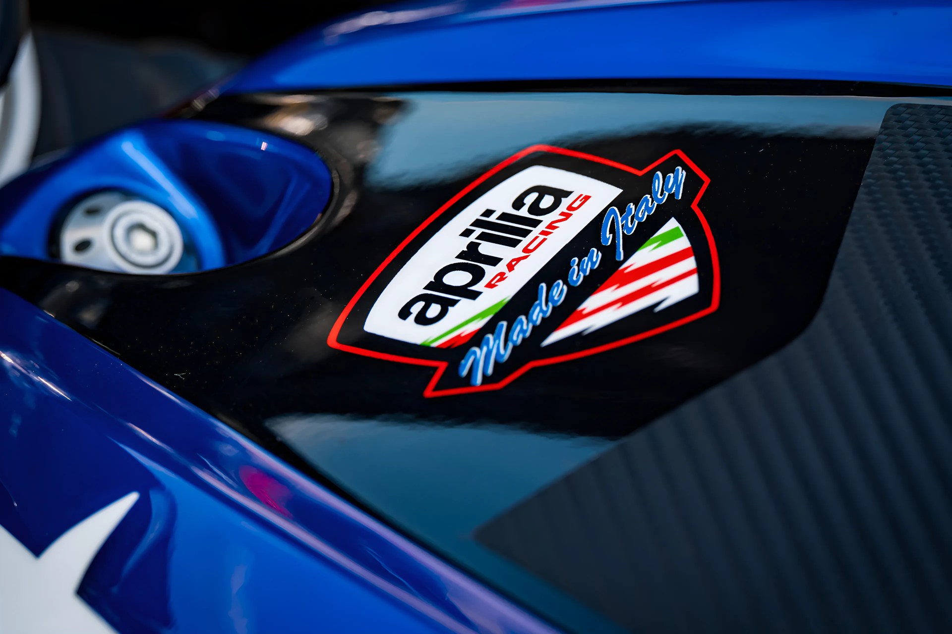 Close-up of a blue and black surface with an Aprilia Racing "Made in Italy" logo decal.
