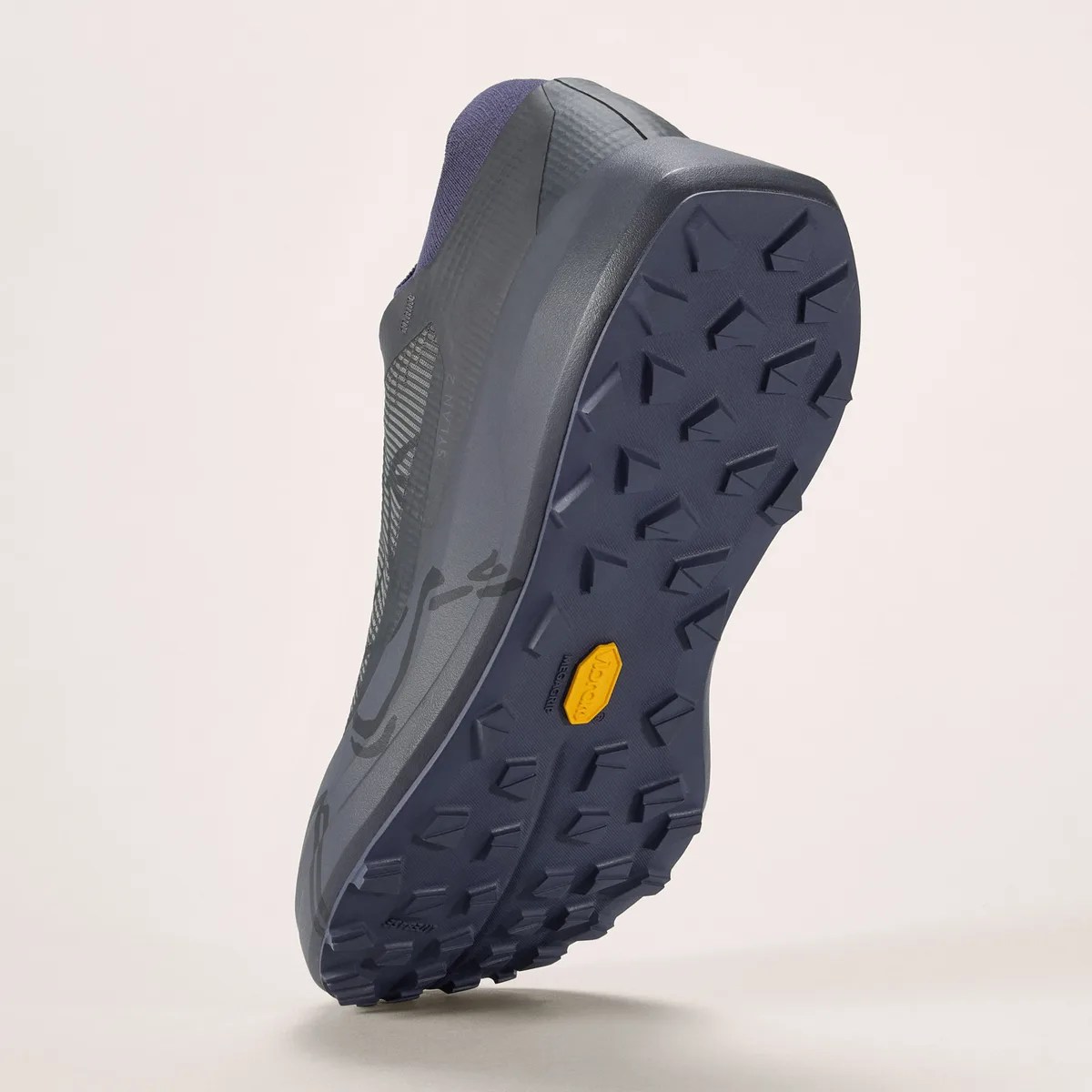 Dark gray and navy trail running shoe sole with deep lugs and a yellow Vibram logo.