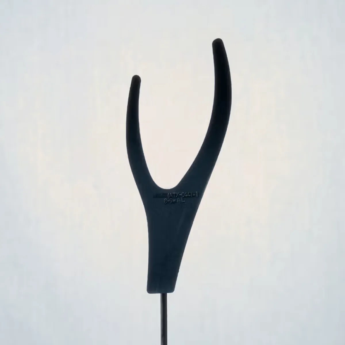 Black plastic tuning fork-shaped tool with a thin metal rod attached.