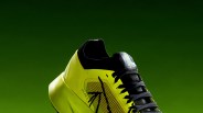 Yellow and black Arc'teryx Sylvan 2 running shoe with black laces on a green background.