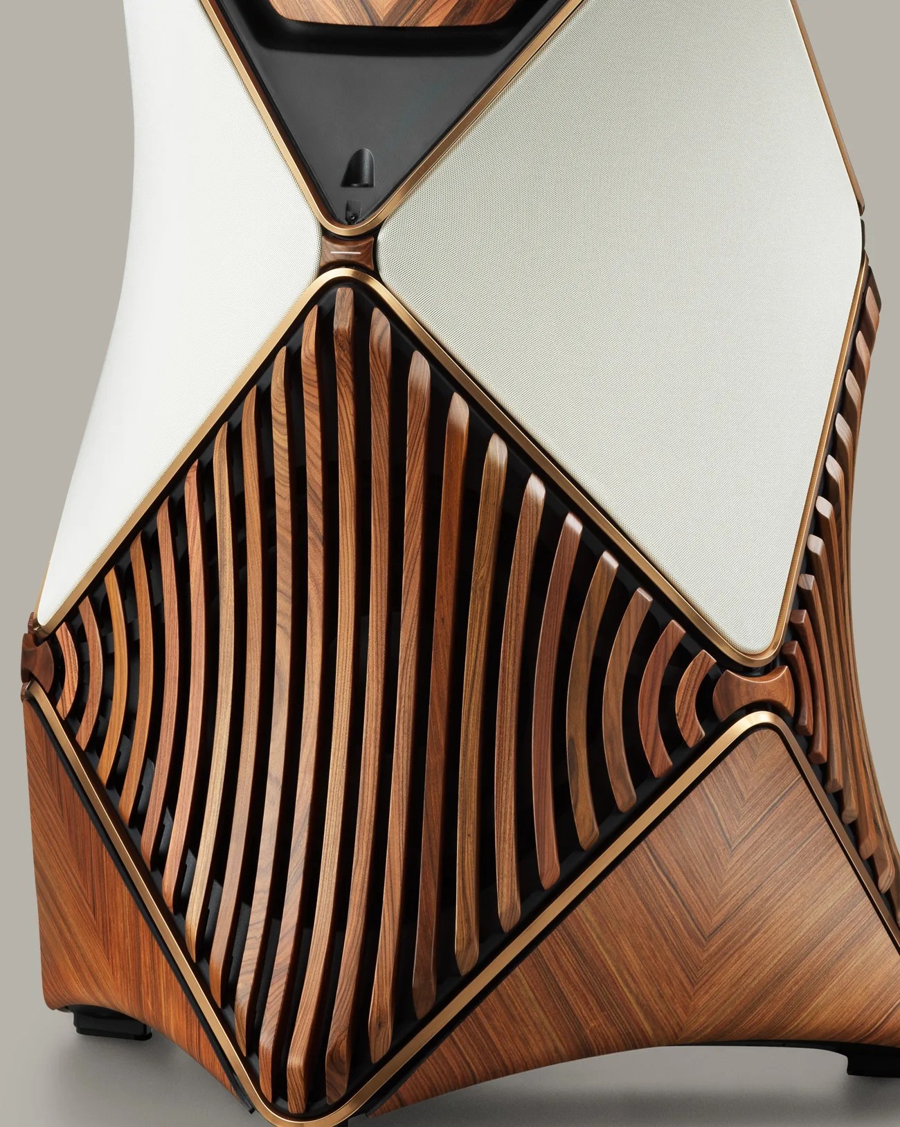 Close-up of a speaker with a wooden slatted grille, white fabric panels, and bronze trim.