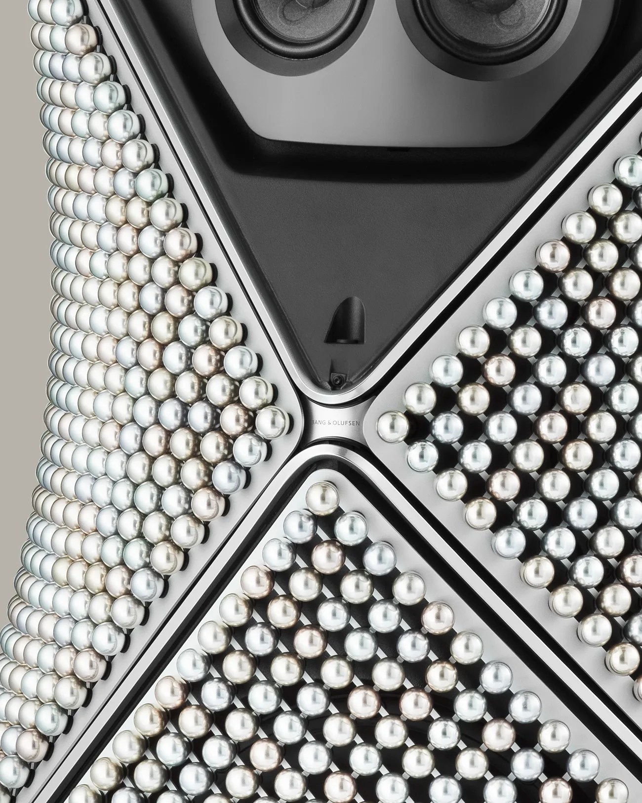 Close-up of a Bang & Olufsen speaker grille adorned with rows of shiny metallic spheres.