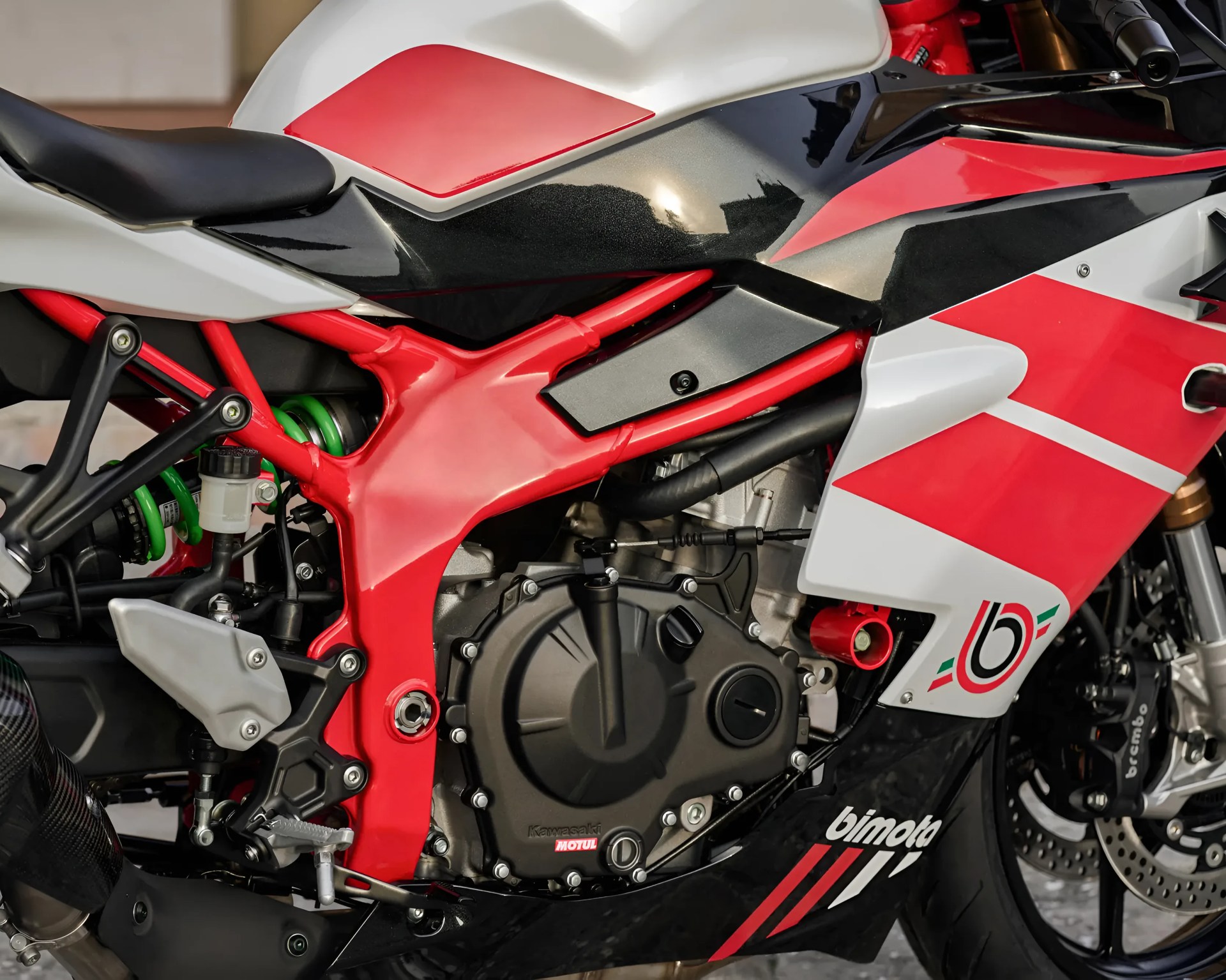 Close-up of a red, white, and black Bimota motorcycle engine and frame with Kawasaki and Motul branding.