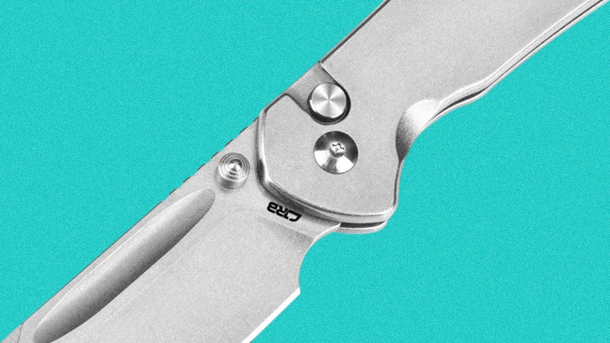 Close-up of a silver folding knife blade and handle with visible screws and a thumb stud on a turquoise background.