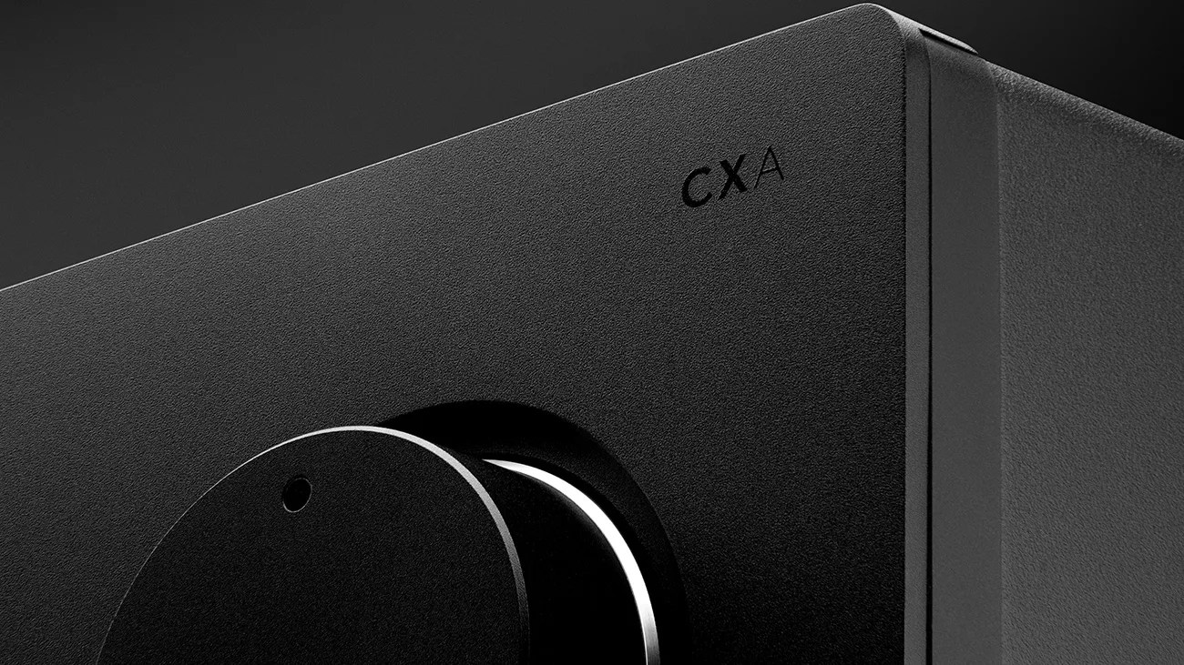Close-up of a black textured audio device with a large round knob and "CXA" printed on the front panel.