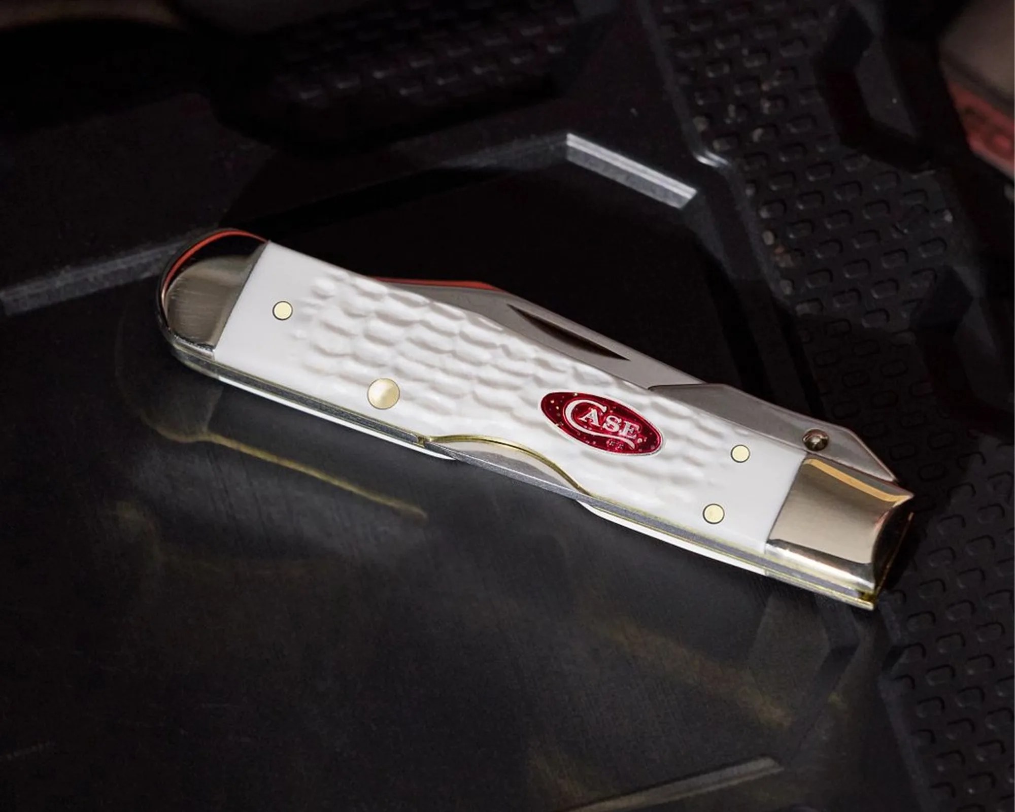 White folding pocket knife with textured handle and red Case logo on a dark surface.