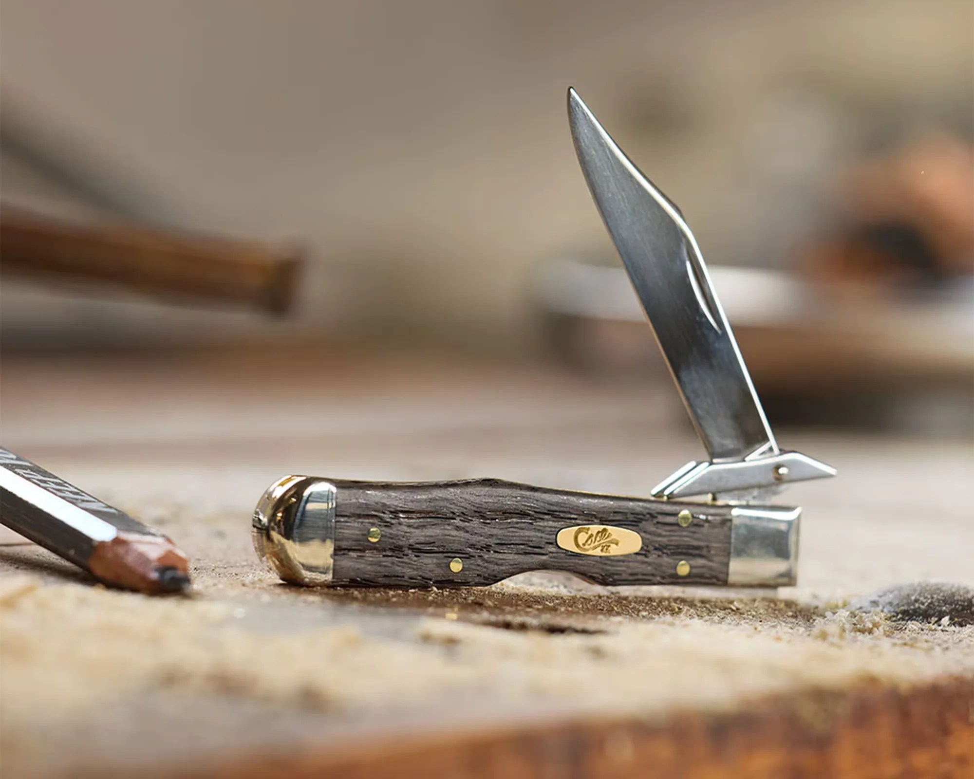 Folding pocket knife with a wooden handle and metal bolsters, blade partially open on a wooden surface.