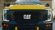 Front view of a yellow CAT truck with black grille and distinctive LED headlights.