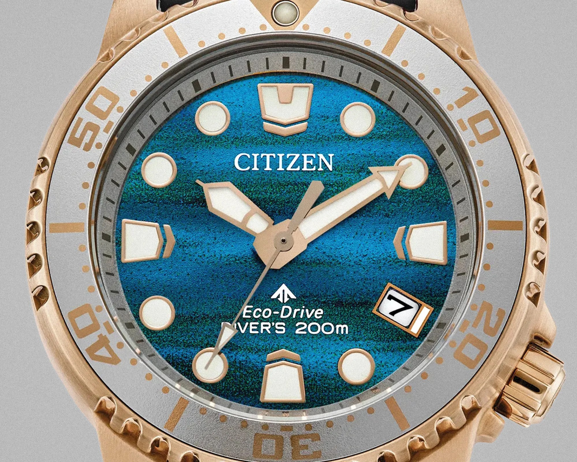 Close-up of a Citizen Eco-Drive diver's watch with a blue textured dial, gold-tone hands, and a date window at 4 o'clock.