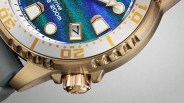 Close-up of a gold-tone watch bezel and crown with a blue-green dial showing date "7" and 200m water resistance.
